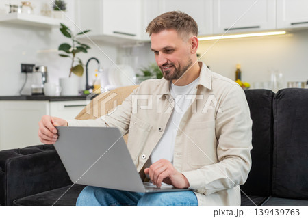 Young man opens laptop starts work boots system types fast smiles with confidence focused remote job Young man opens laptop starts work boots system types fast smiles with confidence focused remote job 139439763