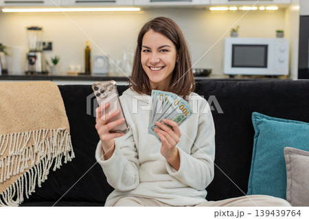 Woman counts money dollar cash checks rate on smartphone smiles plans dream buy salary savings bonus Woman counts money dollar cash checks rate on smartphone smiles plans dream buy salary savings bonus 139439764