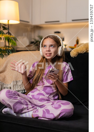 Teenager girl enjoys music with wireless headphones from smartphone smiles moves dances happy rhythm Teenager girl enjoys music with wireless headphones from smartphone smiles moves dances happy rhythm 139439787