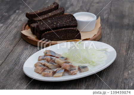 Pieces of salted herring with onions and garlic croutons. 139439874