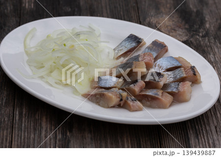 Salted herring with onions on a white plate, the perfect appetizer for vodka. Salted herring with onions on a white plate, the perfect appetizer for vodka. 139439887