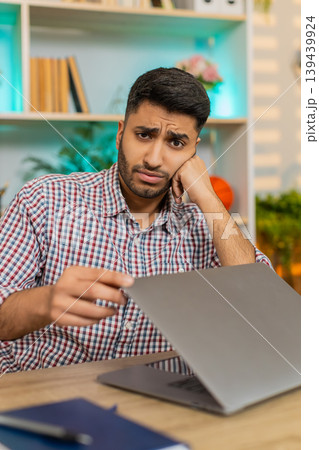 Indian man on home table closing laptop with frustration from tiring routine remote workload stress 139439924