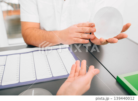 plastic surgeon demonstrates breast implants to a patient for her new breast. plastic surgeon demonstrates breast implants to a patient for her new breast. 139440012