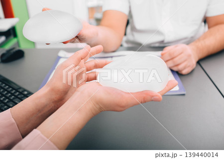plastic surgeon demonstrates breast implants to a patient for her new breast. plastic surgeon demonstrates breast implants to a patient for her new breast. 139440014