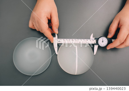 Surgeon measure size silicone breast implants, close-up, view from above. 139440023