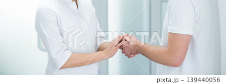 A healthcare provider offers comfort and reassurance to a patient through a supportive handshake in a medical clinic setting 139440056