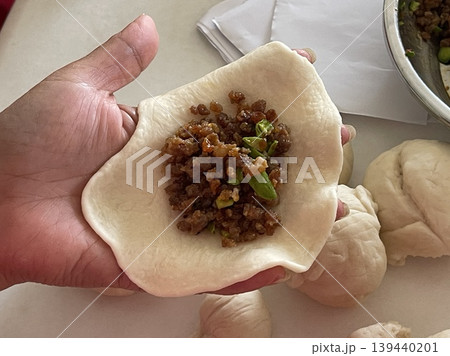 Hand Holding Raw Baozi Dough Filled With Minced Meat And Petai 139440201