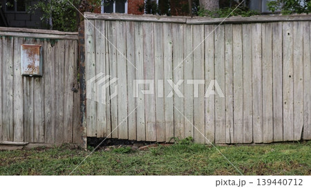 Antique rustic fence with gate and rusty iron mailbox, texture of gray rustic fence with oxidized metal letter container. 139440712