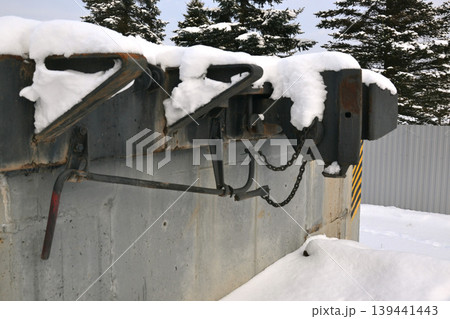 Automatic coupling part rests on a wagon covered in snow with trees visible in the background on a cold winter day. Automatic coupling part rests on a wagon covered in snow with trees visible in the background on a cold winter day. 139441443