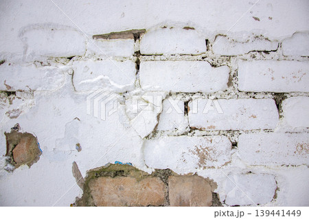 Texture wall of bricks shows visible cracks and peeling sections where paint has come off. This is seen in a building interior during the day. Texture wall of bricks shows visible cracks and peeling sections where paint has come off. This is seen in a building interior during the day. 139441449