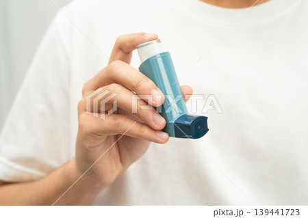 Asthma and chronic obstructive pulmonary disease COPD, Asian young man using metered dose inhaler MDI. 139441723