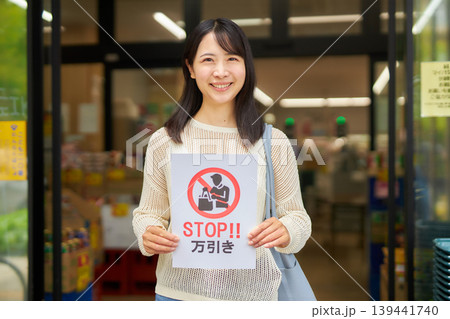 スーパーマーケットの前で食品ロスのプラカードを持つ若い女性 139441740