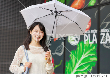 日傘をさしてスーパーマーケットへ行く若い女性 139441741