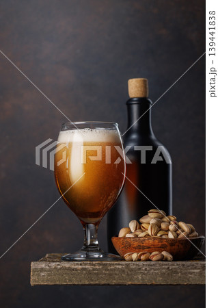 Beer glass with foam and bottle with pistachios Beer glass with foam and bottle with pistachios 139441838