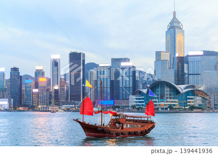 Traditional wooden junk boat with red sails against Hong Kong skyline during sunset Traditional wooden junk boat with red sails against Hong Kong skyline during sunset 139441936