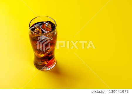 Cola glass with ice on yellow background Cola glass with ice on yellow background 139441972