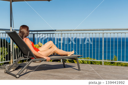 Woman sunbathing on veranda with ocean view 139441992