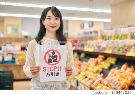 スーパーマーケットの商品の前で万引き防止のプラカードを持つ若い女性 139442029