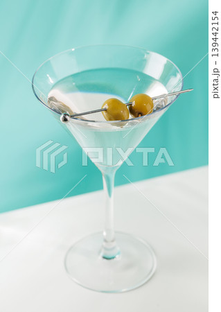 Classic martini cocktail with olives in glass on blue background Classic martini cocktail with olives in glass on blue background 139442154