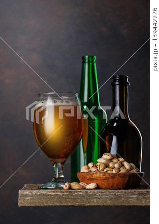 Beer glass with foam and bottles with pistachios Beer glass with foam and bottles with pistachios 139442226