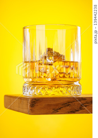 Whiskey glass with ice on yellow background minimal drink still life Whiskey glass with ice on yellow background minimal drink still life 139442238