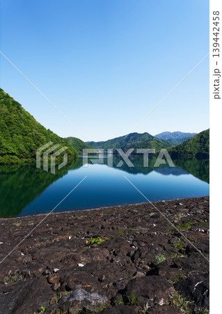 岩場の湖岸から見る新緑の山と湖面の映り込み 岩場の湖岸から見る新緑の山と湖面の映り込み 139442458
