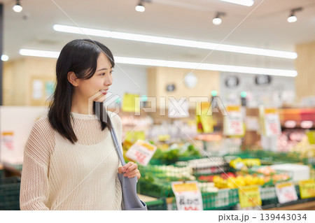 スーパーマーケットでスマホを見ながら買い物をする若い女性 スーパーマーケットでスマホを見ながら買い物をする若い女性 139443034