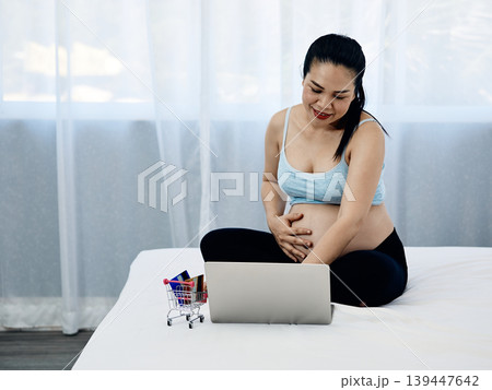 Pregnant woman using laptop for online shopping and digital payment at home, ecommerce lifestyle concept with credit cards, prenatal preparation and modern family finance management Pregnant woman using laptop for online shopping and digital payment at home, ecommerce lifestyle concept with credit cards, prenatal preparation and modern family finance management 139447642