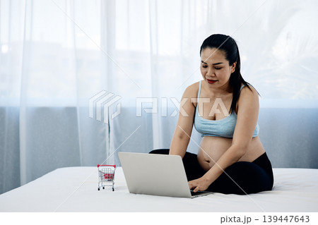 Pregnant woman using laptop for online shopping at home, ecommerce and digital lifestyle concept with modern motherhood, prenatal preparation and family financial planning 139447643