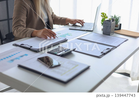 Professional Businesswoman Reviewing Financial Reports and Data Analysis in Modern Office. Professional Businesswoman Reviewing Financial Reports and Data Analysis in Modern Office. 139447743