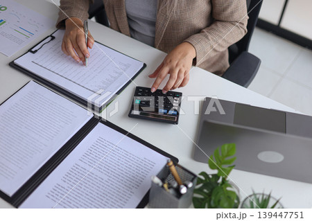 Professional Businesswoman Calculating and Analyzing Financial Documents in the Office. Professional Businesswoman Calculating and Analyzing Financial Documents in the Office. 139447751
