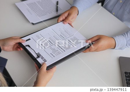 Close-up Job Interview, Female Candidate Handing Resume to Hiring Manager. Close-up Job Interview, Female Candidate Handing Resume to Hiring Manager. 139447911
