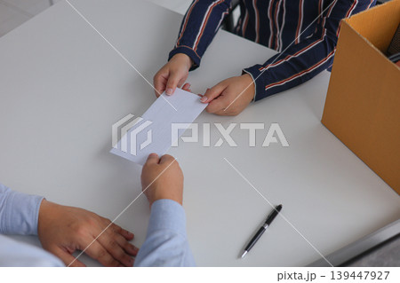 Female Employee Submitting a Formal Resignation Letter or Document to an Executive or Manager. Female Employee Submitting a Formal Resignation Letter or Document to an Executive or Manager. 139447927