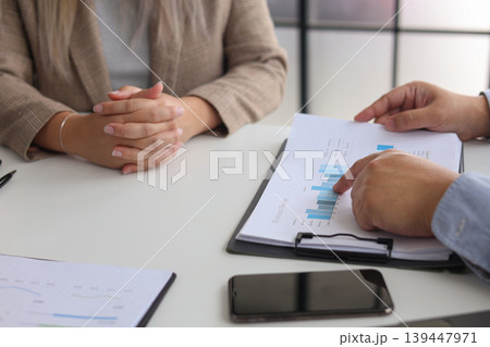 Close-up of Business People Reviewing Performance Graphs and Analyze Data for Business Planning at Office. Close-up of Business People Reviewing Performance Graphs and Analyze Data for Business Planning at Office. 139447971