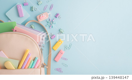 Pastel school supplies spilling from backpack on blue background Pastel school supplies spilling from backpack on blue background 139448147