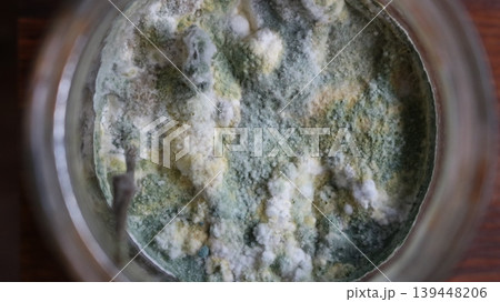 Blue mold on the surface of canned food in an open glass jar, top view, dangerous microorganisms in expired food or canned goods, view of moldy product Blue mold on the surface of canned food in an open glass jar, top view, dangerous microorganisms in expired food or canned goods, view of moldy product 139448206