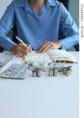 Three stacks of coins arrange separated on the table while businessman writing in a notebook. Concept for financial planning or budgeting Three stacks of coins arrange separated on the table while businessman writing in a notebook. Concept for financial planning or budgeting 139448531