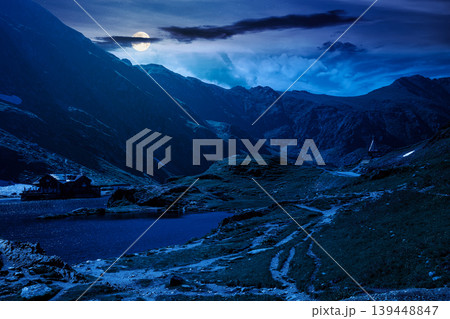 beautiful alpine scenery of fagaras mountains at night. full moon over lake in romania mountain landscape. summer weather with dark sky. rippled water near rocky slope. mysterious travel background beautiful alpine scenery of fagaras mountains at night. full moon over lake in romania mountain landscape. summer weather with dark sky. rippled water near rocky slope. mysterious travel background 139448847