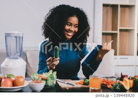 Young nutritionist showing bell peppers during an online video call consulting about healthy eating, sitting at home at a table with vegetables, laptop and measuring tape Young nutritionist showing bell peppers during an online video call consulting about healthy eating, sitting at home at a table with vegetables, laptop and measuring tape 139448920