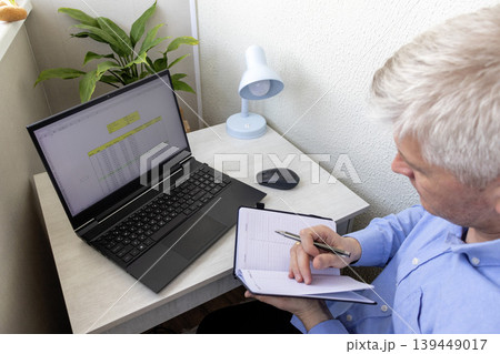 Man studying numbers on the laptop screen on the modern desk showing spreadsheet with loan amortization table 139449017