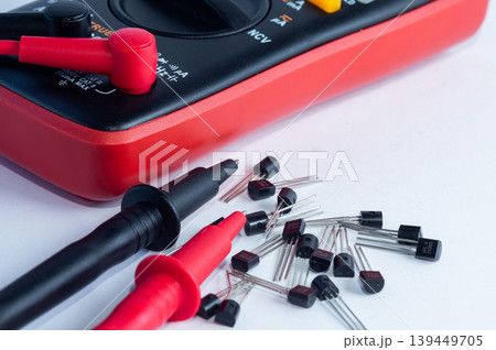 Multimeter with measurement probes and transistors on a white background 139449705