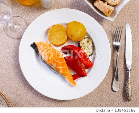 Salmon fillet served with potatoes, peppers and eggplant 139453568