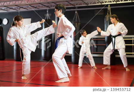 Boy and girl train to perform defensive karate installations and attacking combat techniques Boy and girl train to perform defensive karate installations and attacking combat techniques 139453712