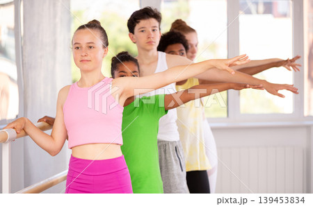 Teenage girl practicing position holding by ballet barre during workout session 139453834