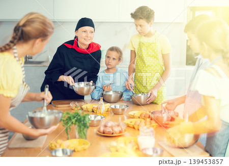 At cooking course, woman cook in black suit tells children about rules of cooking fluffy pancakes. At cooking course, woman cook in black suit tells children about rules of cooking fluffy pancakes. 139453857