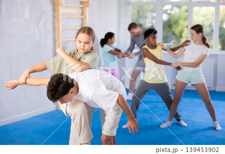 Girls and boys learns to do power grip with trainer during a self-defense lesson in gym 139453902
