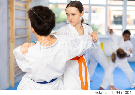 Teenage girl practicing fighting techniques during martial arts sparring with boy 139454004