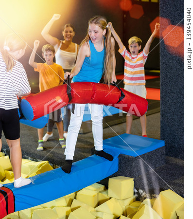 Team of friends playing with inflatable sticks in amusement park Team of friends playing with inflatable sticks in amusement park 139454040