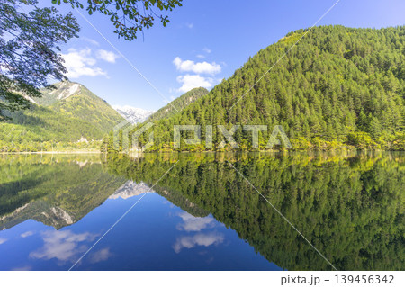 Amazing view of Mirror Lake with crystal clear water among mountains and evergreen woods in Jiuzhaigou nature reserve (Jiuzhai Valley National Park),China. Amazing view of Mirror Lake with crystal clear water among mountains and evergreen woods in Jiuzhaigou nature reserve (Jiuzhai Valley National Park),China. 139456342
