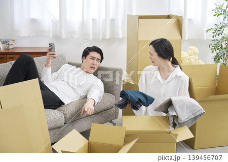 引っ越し作業中に怠ける男性と荷造りする女性 139456707